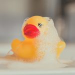 Self Care is More than a Bubble Bath Blog Post Header Image for Sage & Fettle Ayurveda with rubber duck covered in bubbles